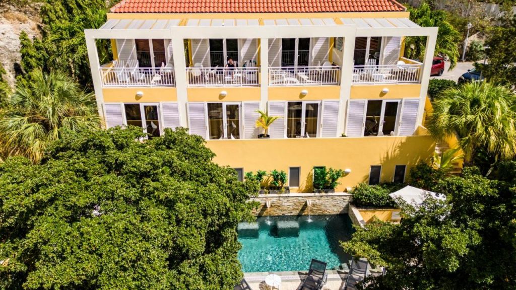 Fachada do hotel para lua de mel em Curaçao, com piscina e quartos com varanda.