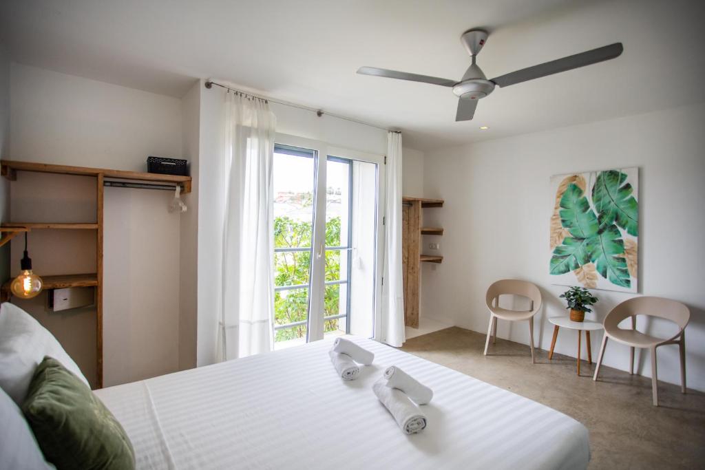Quarto com cama grande de casal, ventilador de teto, cadeiras e varanda em hotel de lua de mel em Curaçao