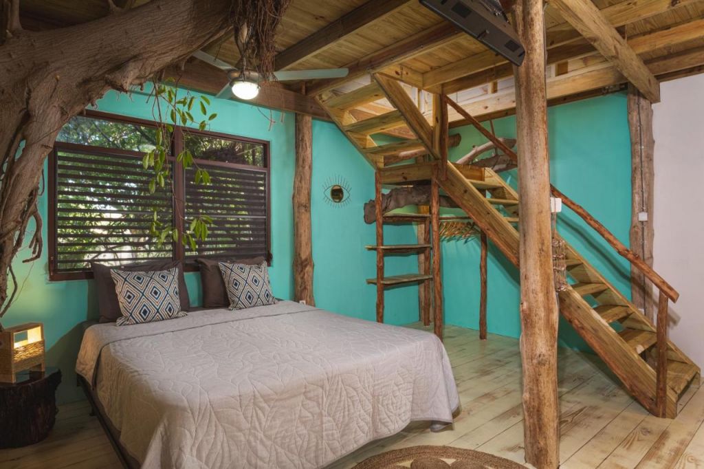 Chalé com cama de casal, detalhes em madeira e tronco da árvore dentro em hotéis em Curaçao