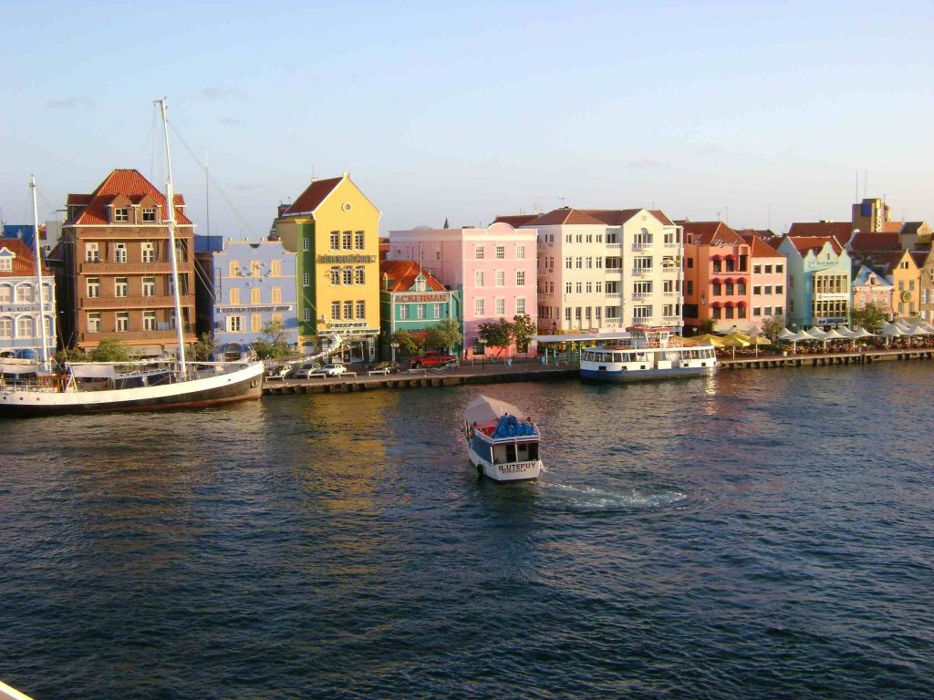 Visual das casinhas coloridas de Curaçao com barquinho no canal. 